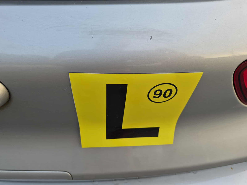 Yellow learner's magnets with number 90 on a car's rear "L's"