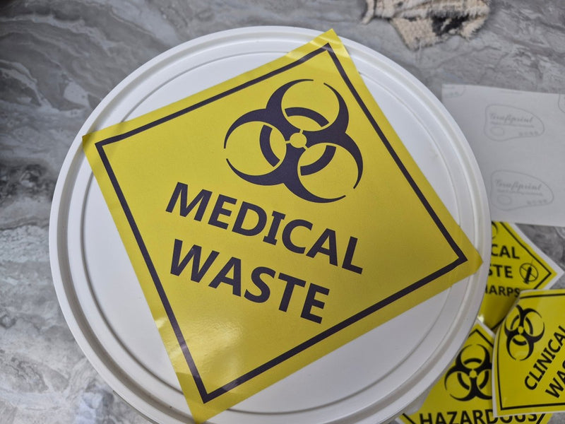Yellow 'Medical Waste' sign with biohazard symbol on a white container lid.