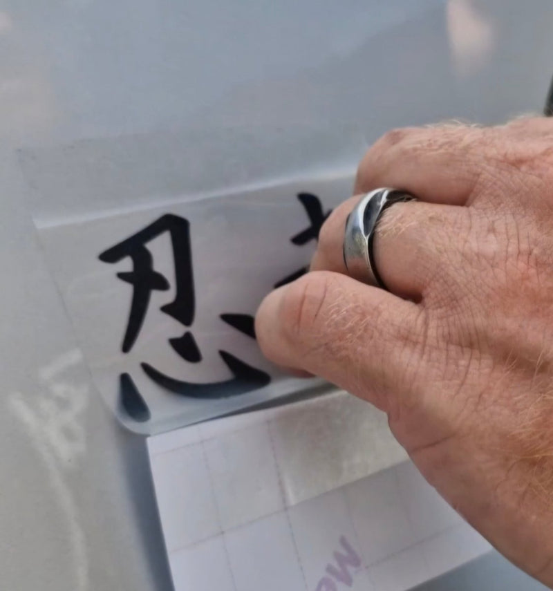 Hand with a ring holding a transparent sheet with black characters against a light background