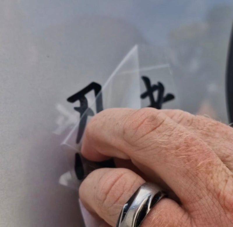Hand with a silver ring pressing on a transparent square with black text against a blurred background
