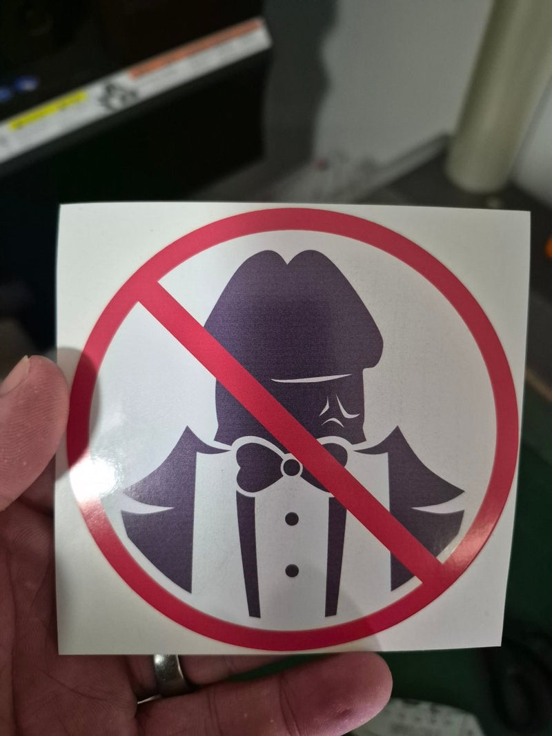 No Dickheads Allowed Prohibition Sticker with a cartoon character wearing a gas mask, held by a hand.