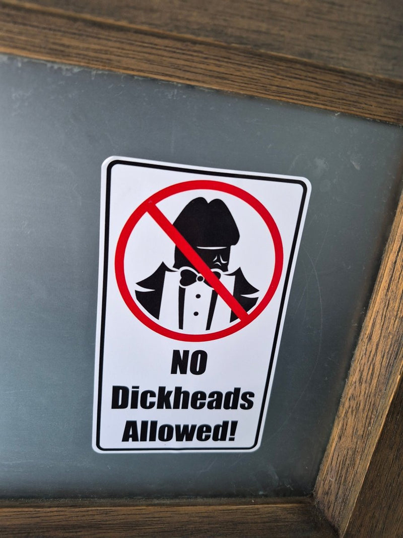 Sign with a prohibition symbol and text 'No Dickheads Allowed!' on a wooden frame.