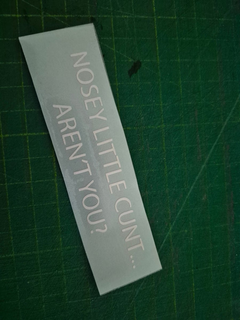 Rectangular decal with offensive text on a green cutting mat