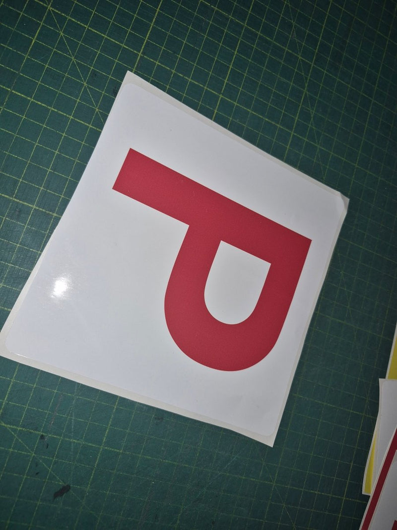 Red 'P' on a white square sheet on a green cutting mat