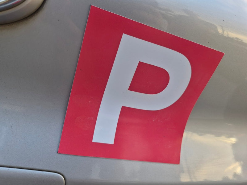 Red and white 'P' plate on a car, indicating a learner driver.