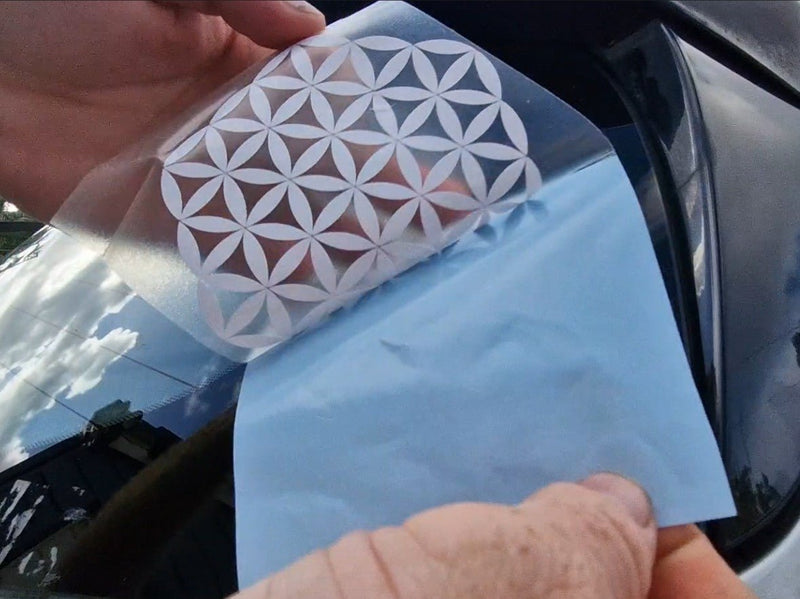 Person holding a car window decal with a geometric design