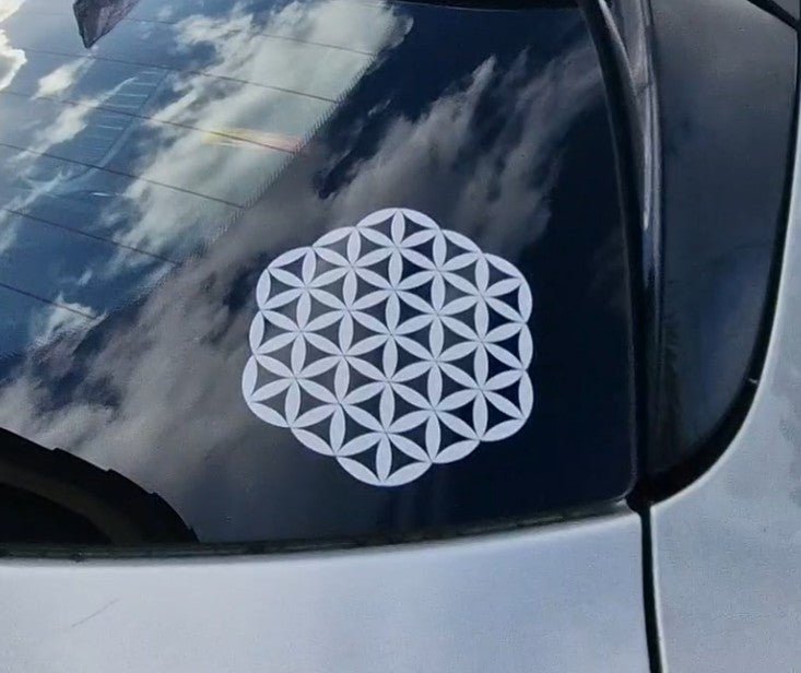 White geometric decal on a car window with a cloudy sky reflection.