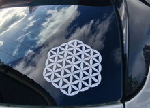 Load image into Gallery viewer, White flower of life symbol on a car window with a blue sky reflection.
