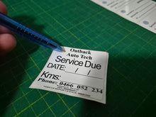 Load image into Gallery viewer, Service due label held by a hand with a pen on a green cutting mat
