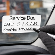 Load image into Gallery viewer, Hand writing on a car window with a service due date label.
