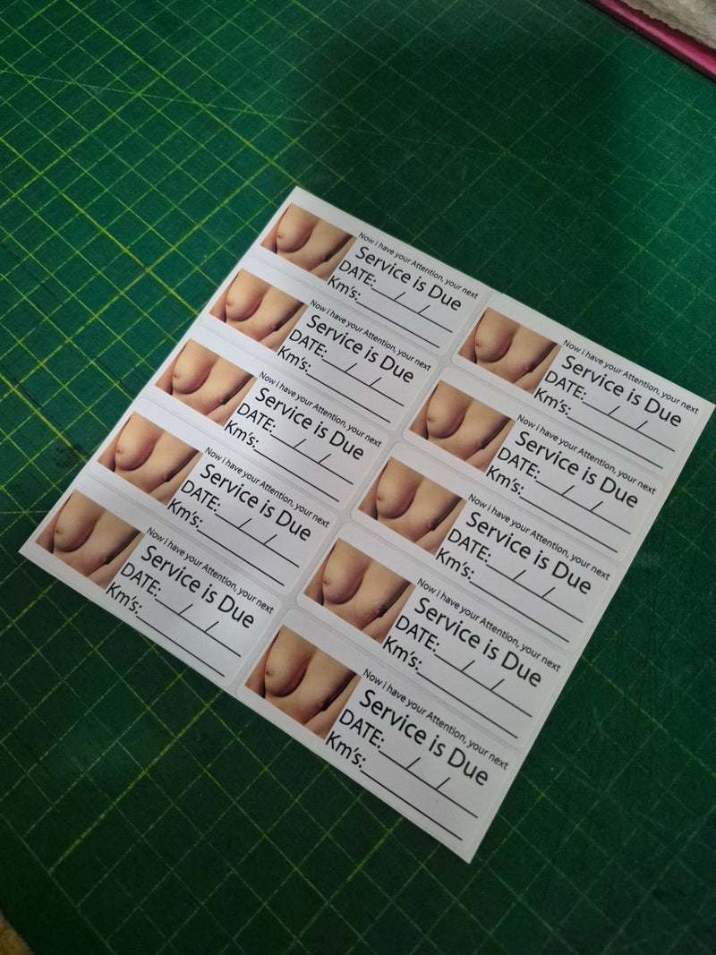 Sheet of 'Service is Due' labels with images of feet on a green cutting mat.