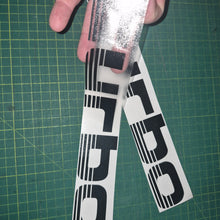 Load image into Gallery viewer, Two 'Turbo' decals being held over a green cutting mat.

