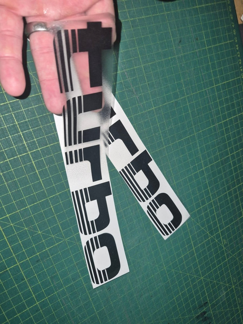 Two 'Turbo' decals held over a green cutting mat.