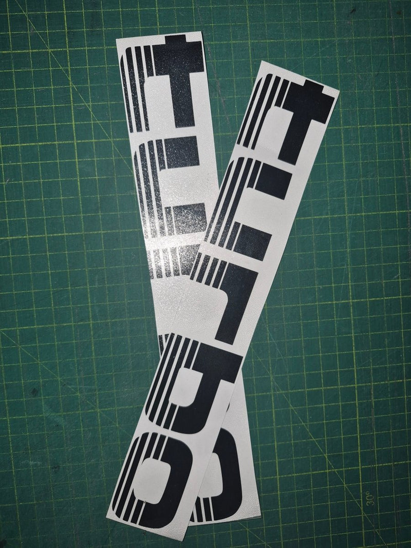 Two black and white decals with 'TURBO' text on a green cutting mat.