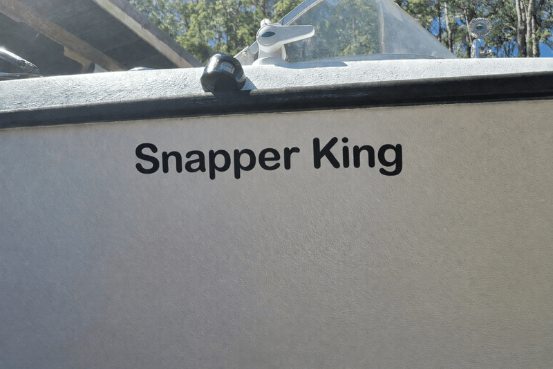 Decal on a Boat's side with 'Snapper King' text, outdoors.