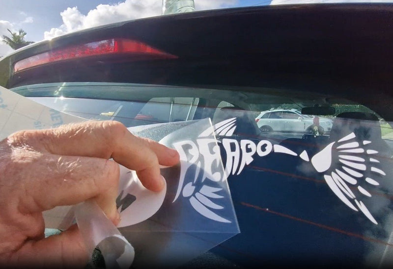 Spearo Sticker Hand holding a white decal with text and graphics, approaching a car window.