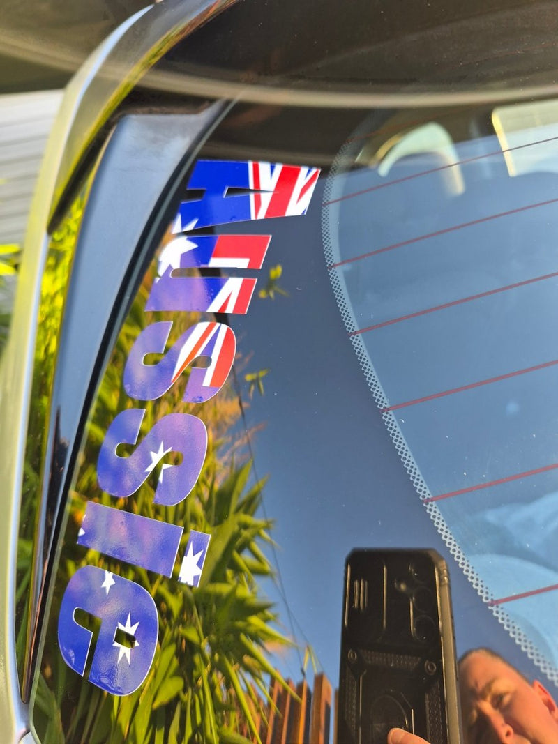 Reflective surface with 'Aussie' text and Australian flag, showing a garden reflection.