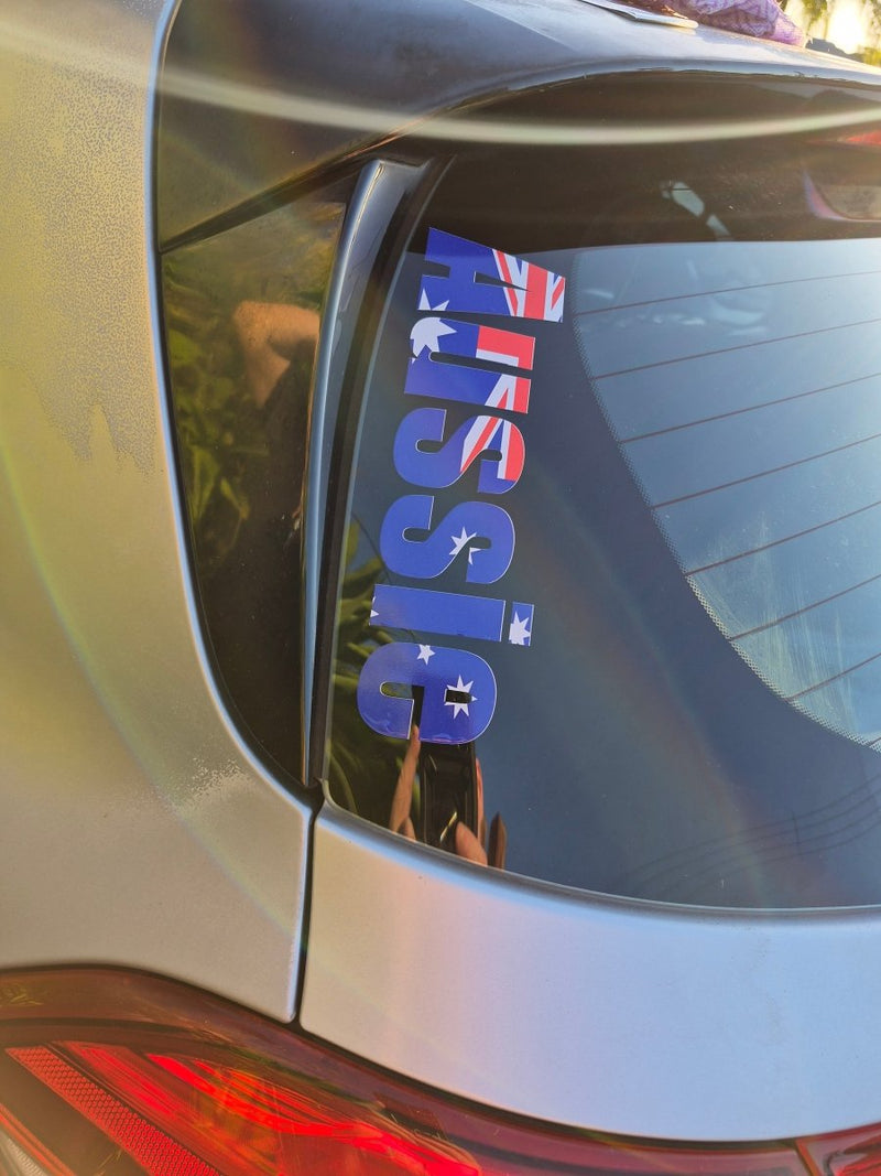 Car window with 'AUSSIE' decal featuring Australian flag colors
