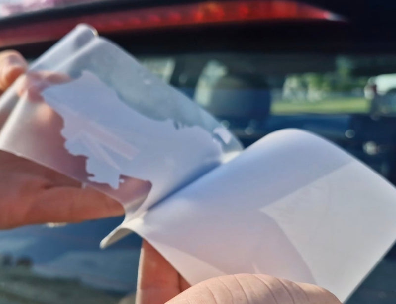Sticker of Australia's flag and map Person holding a white plastic tool with a car in the background