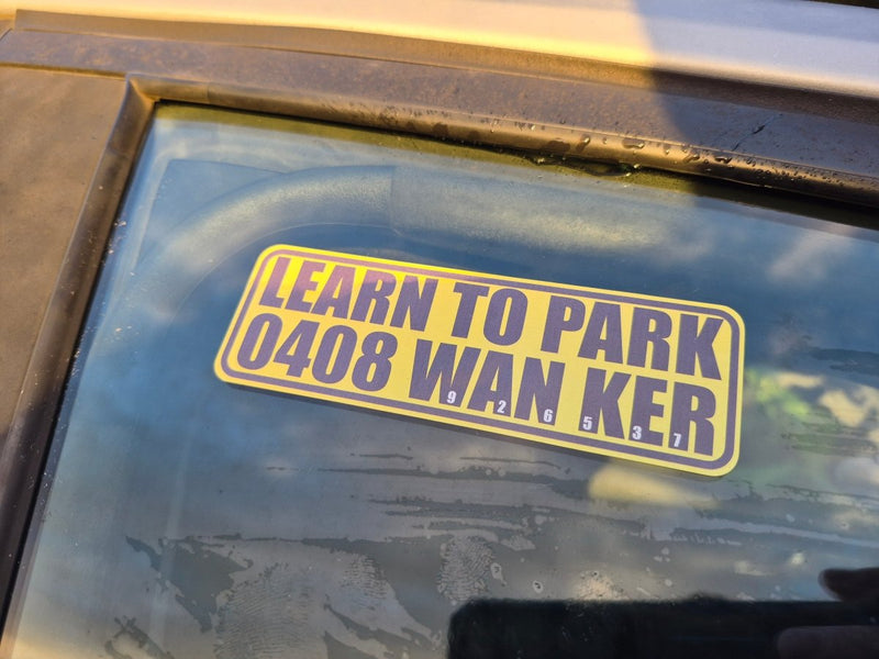 Sticker on a car window with text 'LEARN TO PARK 0408 WAN KER' on a reflective surface.