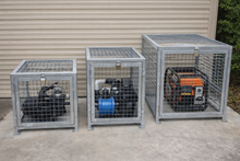 Load image into Gallery viewer, Three metal cages with generators inside against a wall.
