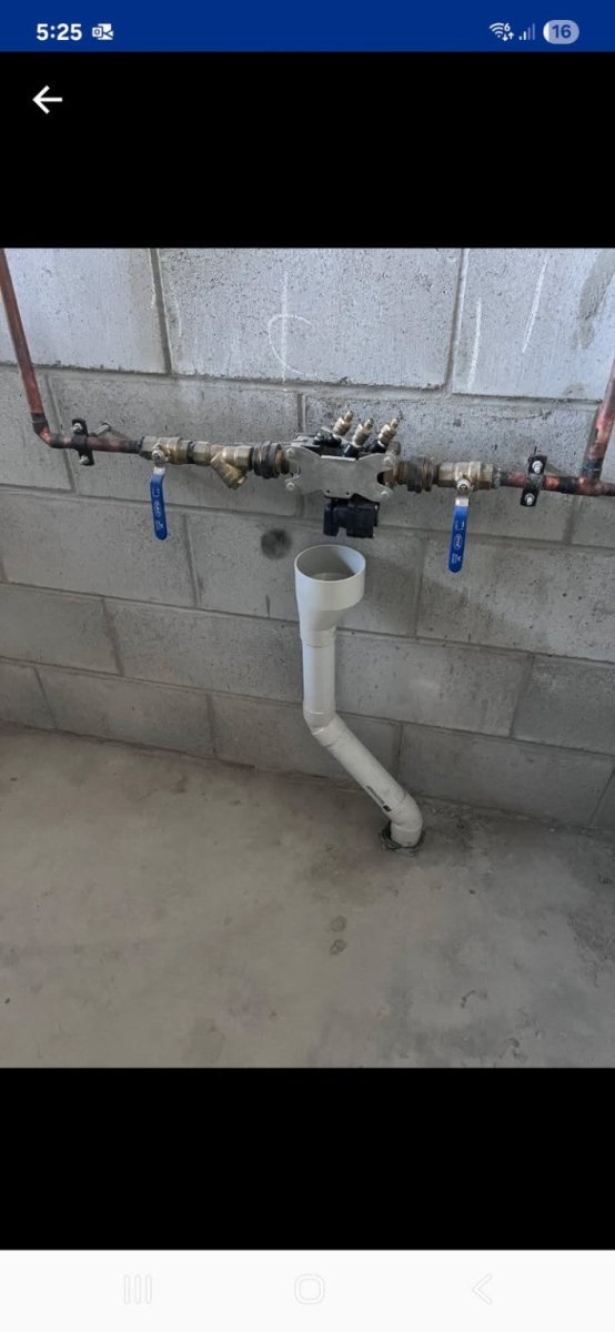 Plumbing system with pipes and valves mounted on a concrete wall.