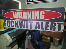 Load image into Gallery viewer, Warning sticker with text 'WARNING FUCKWIT ALERT' held in front of a machine.
