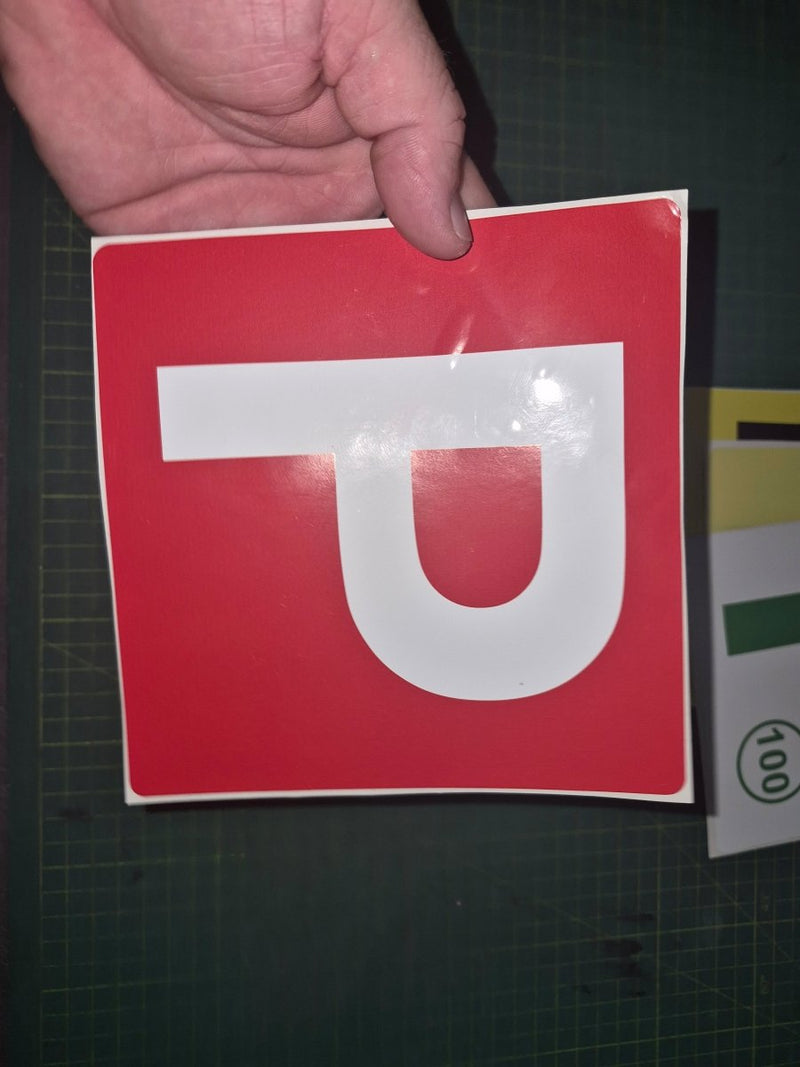 Red square sign with a white 'P' held by a hand on a dark background