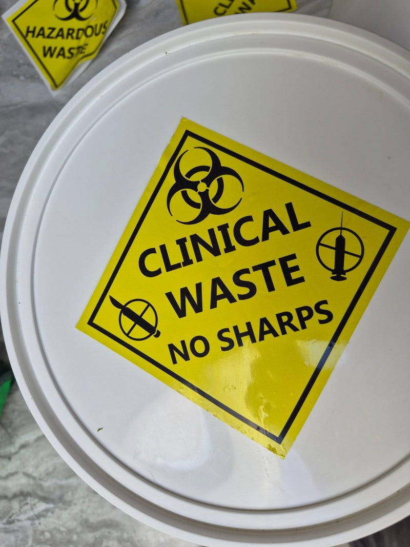 White container with a yellow 'Clinical Waste No Sharps' sign on a gray background