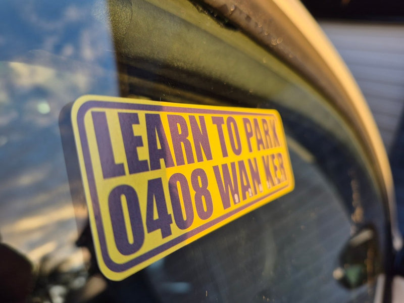 Yellow and black sticker on a vehicle window with text 'LEARN TO PARK 0408 WAN KER'.