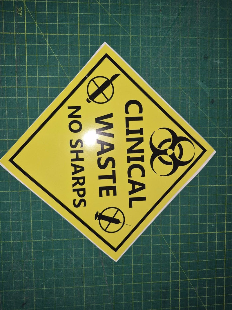 Yellow warning sign with black text and symbols on a green grid background "Yellow clinical waste  no sharps "
