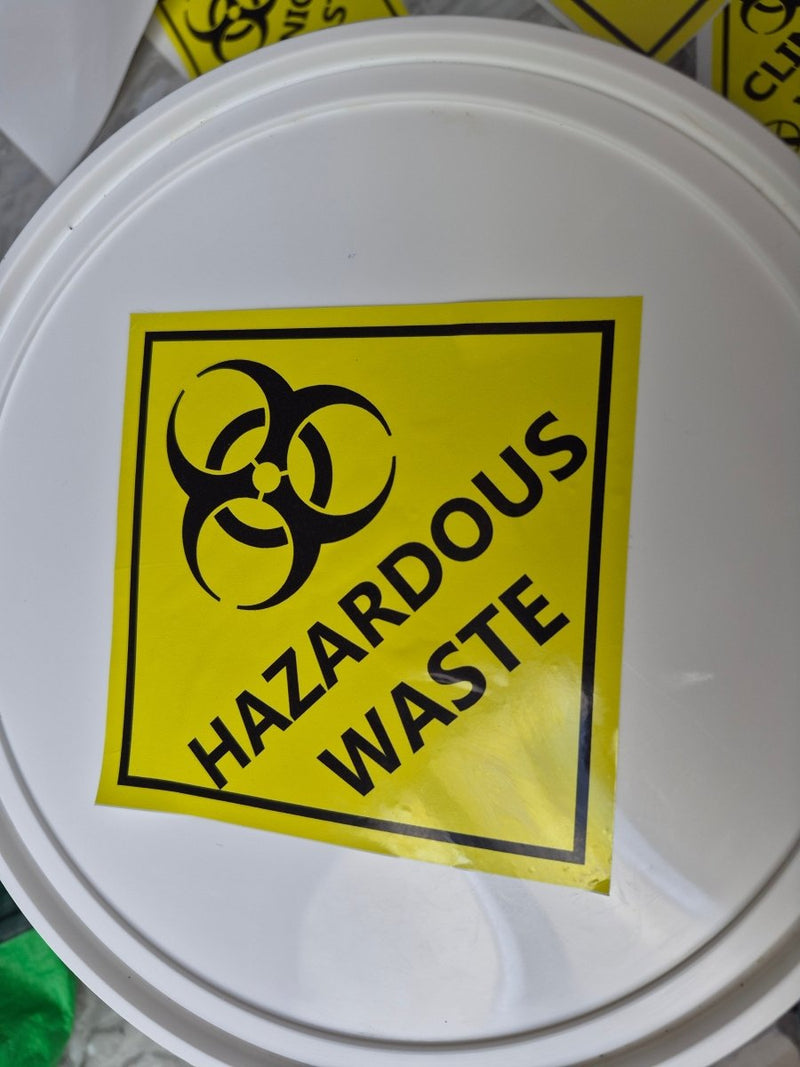 White container lid with a hazardous waste label featuring a biohazard symbol.
