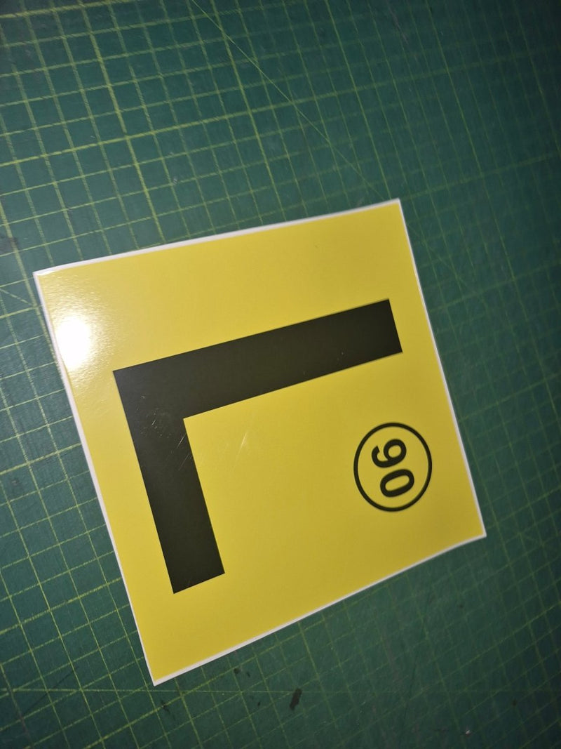 Yellow square with a black 'L' and number 90 on a green grid background