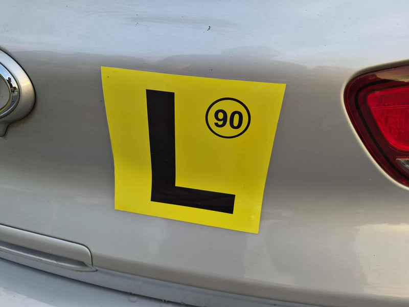 Yellow learner's magnets design 90kms with a black 'L' and number 90 on a car's rear.