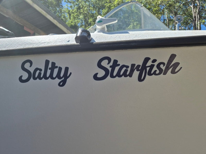 Boat with 'Salty Starfish' decal on a sunny day with trees in the background