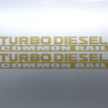 Load image into Gallery viewer, Matte gold Turbo Diesel Common Rail stickers on grey panel
