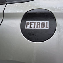 Load image into Gallery viewer, A close-up of a silver car fuel door with a black circular cover featuring a white sticker that reads 'PETROL'.
