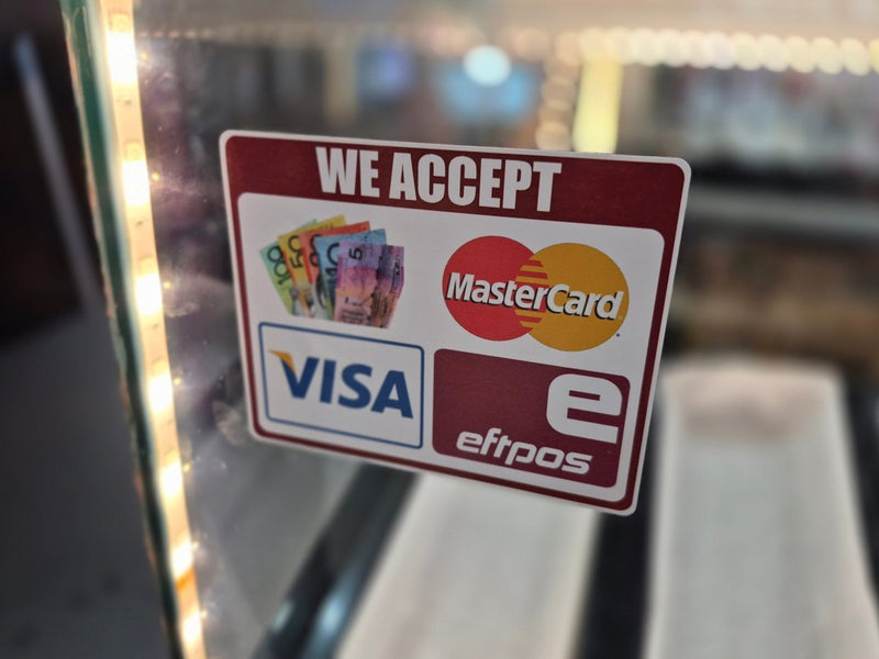 Sign indicating acceptance of various payment methods including Visa, MasterCard, and eftpos on a glass surface.