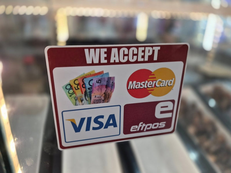 Sticker indicating acceptance of various payment methods including Visa, MasterCard, and eftpos on a blurred background.