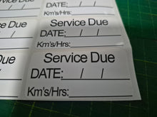 Load image into Gallery viewer, Service due label with fields for date, kilometers, and hours on a green cutting mat.
