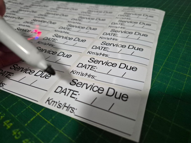 Sheet of labels with 'Service Due' text on a green cutting mat.