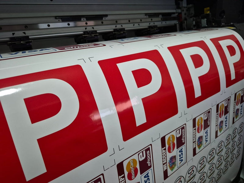 Large roll of paper with red 'P' letters and logos on a printing machine.