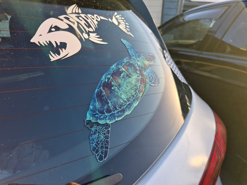 Car window with a turtle decal and another design on a reflective surface