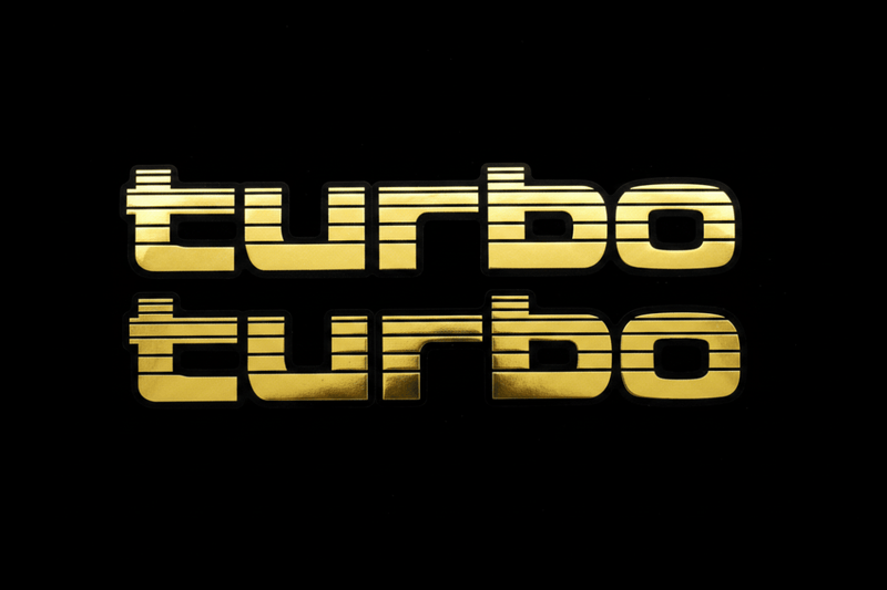 Two gold Turbo stickers flat lay black background