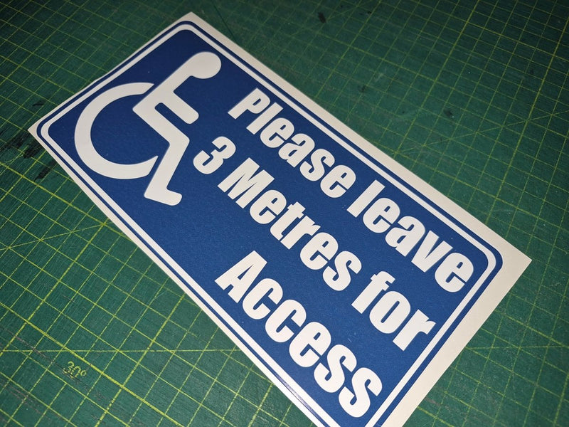 Blue and white sign with wheelchair icon and text on a green cutting mat
